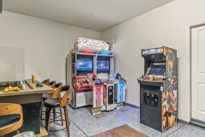 Ein Raum mit Spielautomaten, einem Holztisch und Barhocker.