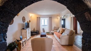 A living room with a stone archway, a sofa, a television, and a window.