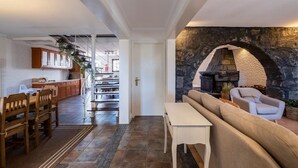 A modern interior with a stone fireplace, wooden furniture, and a kitchen area.