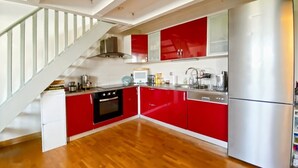 Una cuina moderna amb armaris vermells, un frigorífic d'acer inoxidable i una escala de fusta.
