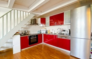 Eine moderne Küche mit roten Schränken, einem Edelstahlkühlschrank und einer Holztreppe.