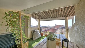Terrassa al terrat amb una pèrgola de fusta, plantes en test, zona de seients i vista a la ciutat.