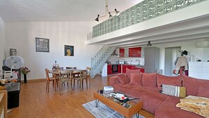 Un saló modern amb zona de menjador, cuina i escala que condueix a un pis superior.