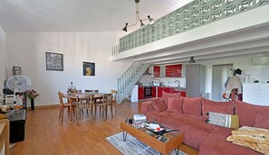 Ein modernes Wohnzimmer mit Essbereich, einer Küche und einer Treppe, die in eine obere Ebene führt.