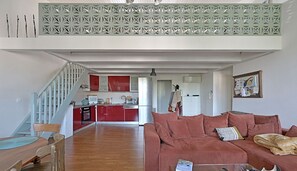 Ein Wohnzimmer mit einem roten Sofa, einem Holzesstisch und einer Küche im Hintergrund.
