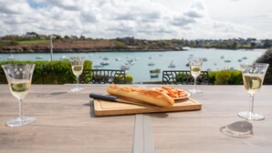 A table with wine glasses and a baguette, overlooking a harbor with boats. - Beautiful Panoramic View of the sea - Portsall (Ploudalmezeau)