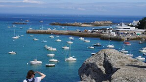 A coastal marina with numerous boats, a rocky foreground, and a building with a flat roof in the background. - Beautiful Panoramic View of the sea - Portsall (Ploudalmezeau)