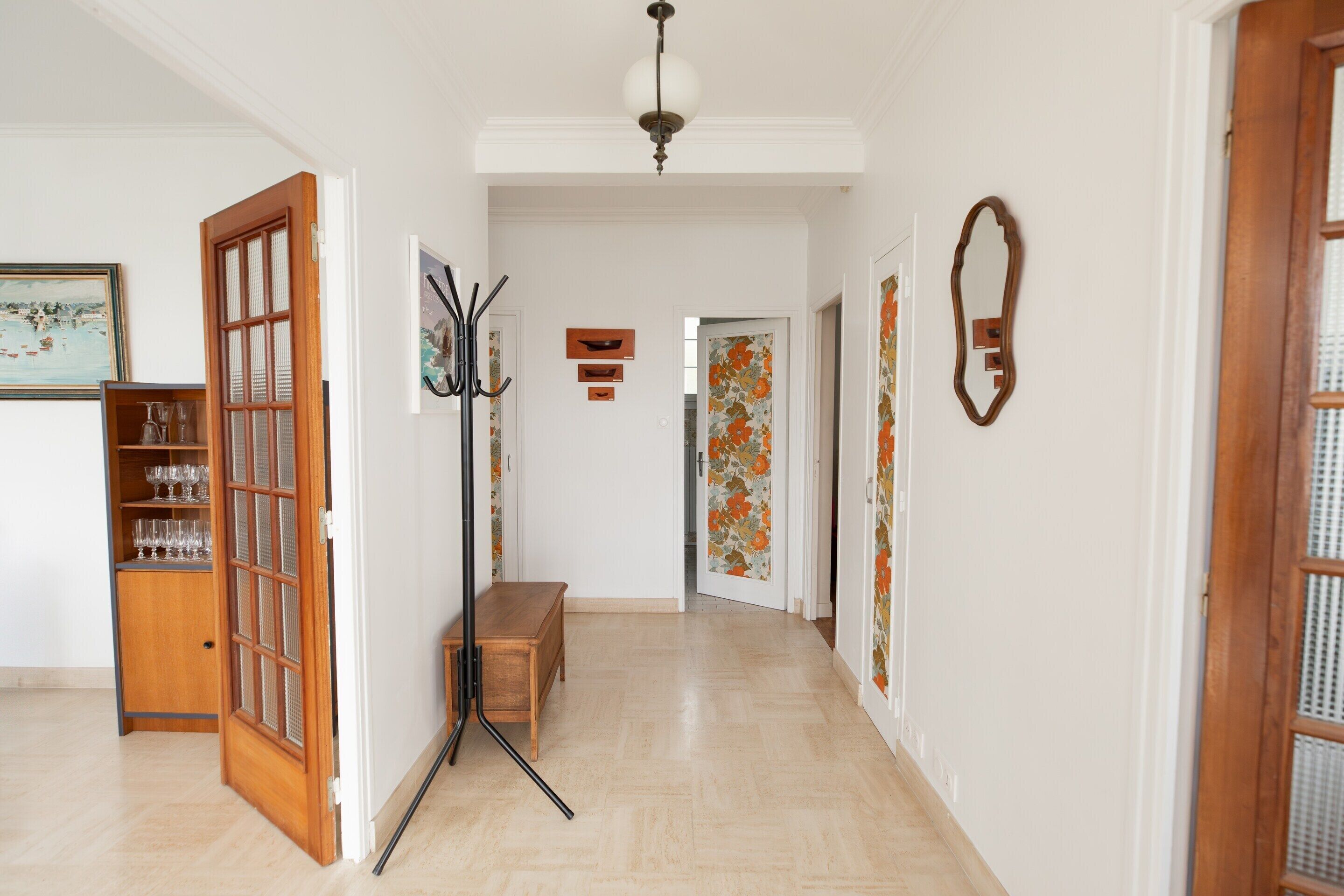 Un pasillo con un banco de madera, un perchero y una puerta con un panel de vidrio.