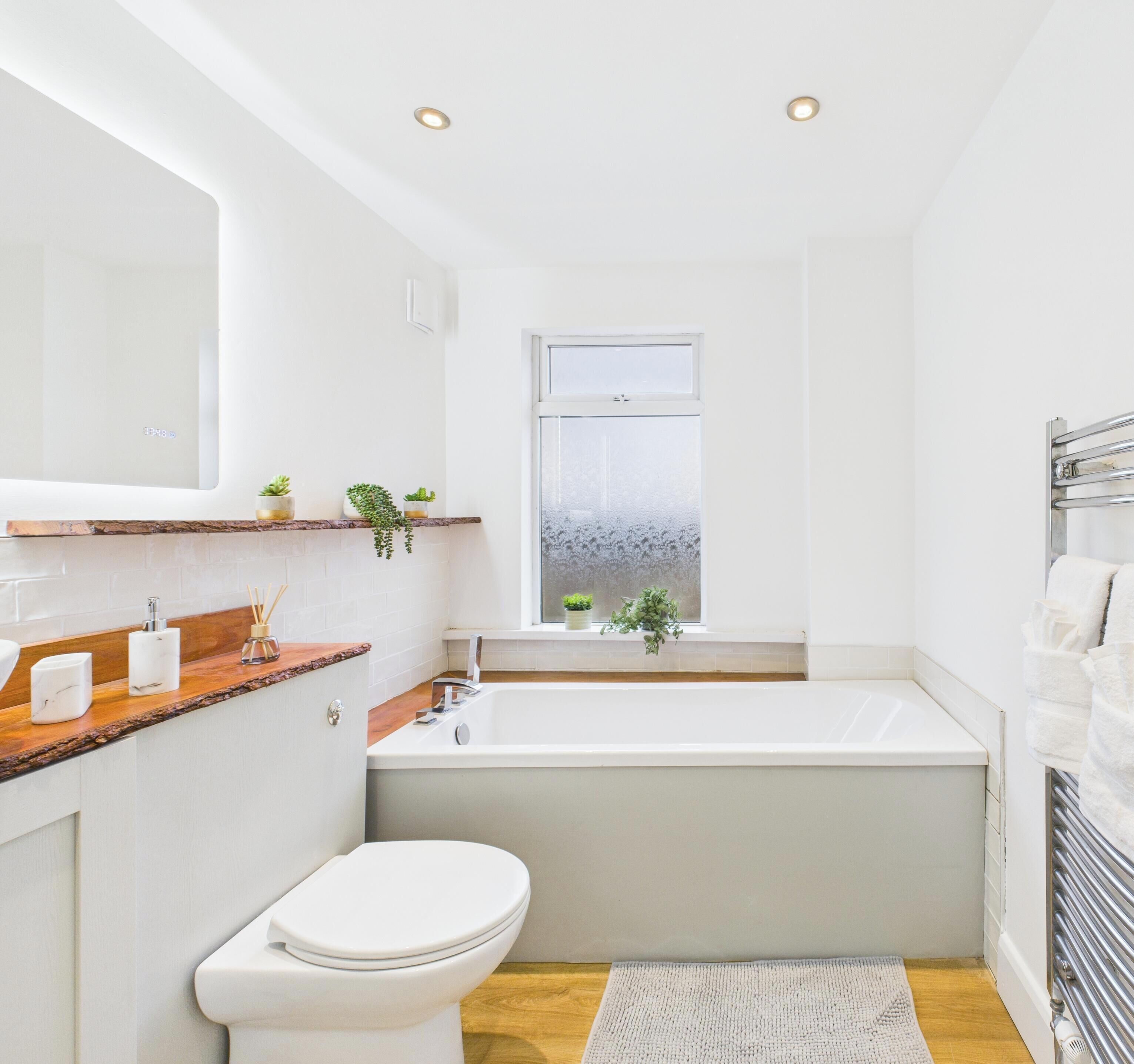 Une salle de bain moderne avec une baignoire, des toilettes et une fenêtre.