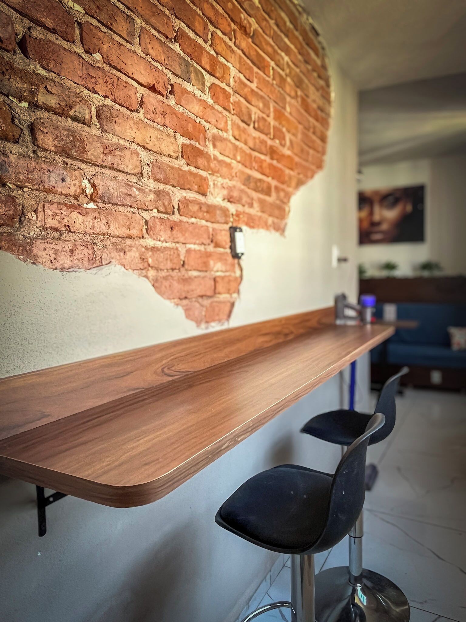 Una zona de bar con mostrador de madera y dos taburetes negros.