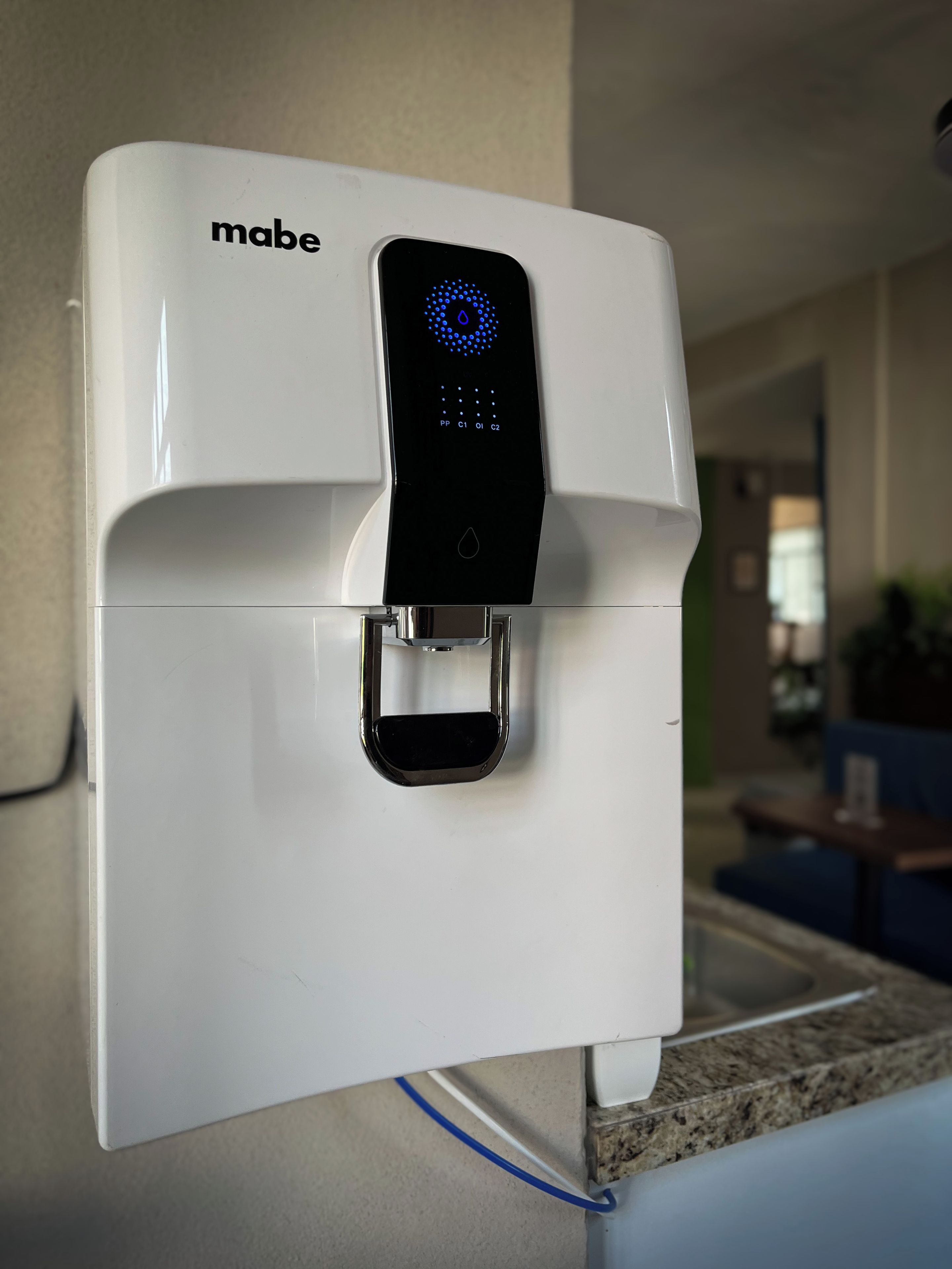 A wall-mounted water dispenser with a digital interface, a power outlet, and a cable.