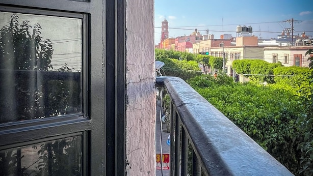 Un balcon donnant sur des immeubles et de la verdure.