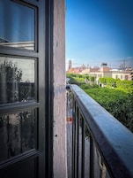 A balcony with a view of buildings and greenery.