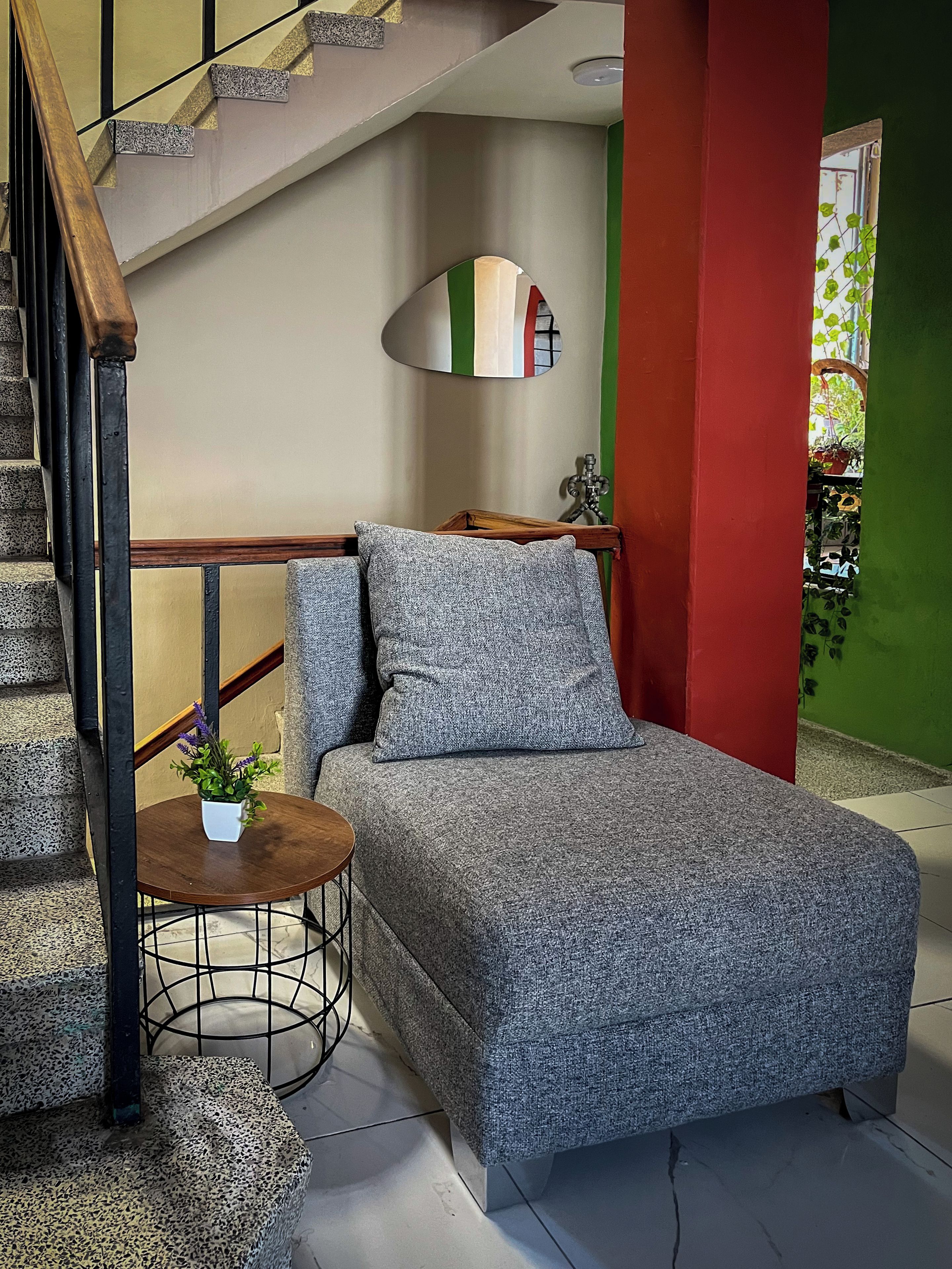 Un dormitorio con una cama, una mesita con una planta, un espejo y una escalera.