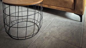 Un salon moderne avec un canapé et une table basse ronde dont le piétement est constitué d’une structure en fil de métal.
