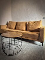 A modern living room with a sofa and a round coffee table with a wireframe base.