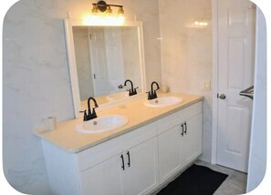 A bathroom with two sinks, a large mirror, and a white vanity with cabinets.