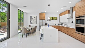 A modern kitchen with a central island, built-in appliances, and large windows. - Stylish Pool Home 4BR Near Siesta Key "Palm Noir" (Sarasota)