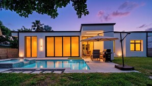 A modern house with a swimming pool, large windows, and outdoor furniture. - Stylish Pool Home 4BR Near Siesta Key "Palm Noir" (Sarasota)