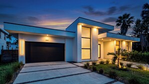A modern house with a garage, large windows, and a well-lit driveway. - Stylish Pool Home 4BR Near Siesta Key "Palm Noir" (Sarasota)