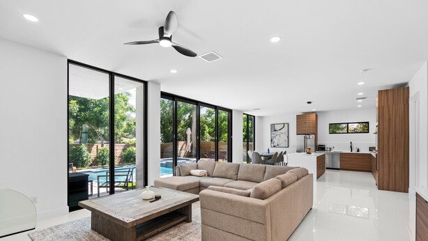 A modern living room with a sectional sofa, a coffee table, and a dining area with a table and chairs. - Stylish Pool Home 4BR Near Siesta Key "Palm Noir" (Sarasota)