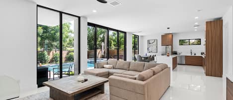 A modern living room with a sectional sofa, a coffee table, and a dining area with a table and chairs.