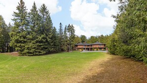 Un chalet doté d’une grande pelouse, entouré de grands arbres.