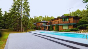 Un bâtiment à deux étages doté d’une piscine, entouré d’arbres.