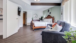 Une chambre à coucher avec un lit, un canapé, une télévision et un luminaire au plafond.