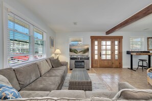 Ein Wohnzimmer mit Sofa, Kamin, Essbereich und Blick ins Freie.