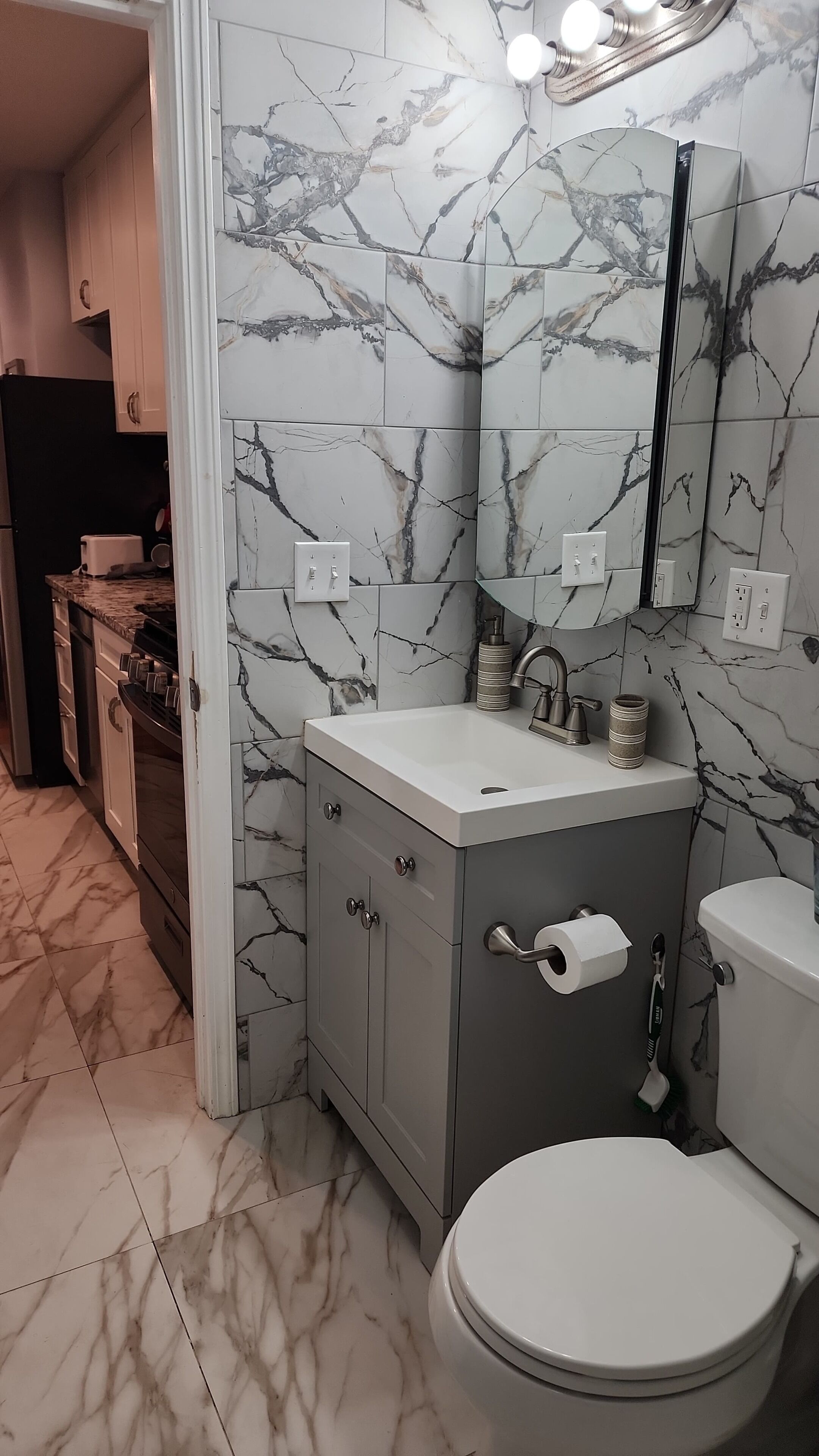 A bathroom with marble walls, a sink, a toilet, and a mirror.