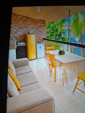A modern living room with a sofa, a dining table, and chairs. There is a brick wall and a window with a view of greenery. - Espaço aconchegante e charmoso em meio à natureza. (Rio de Janeiro)
