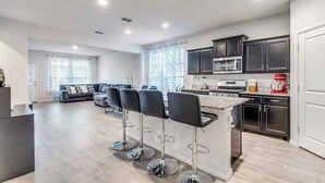 A modern kitchen with dark cabinets, a central island, and bar stools.