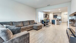 A spacious living area with a large sectional sofa, a dining table with chairs, a kitchen area with a bar, and a separate dining room.