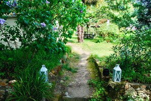 A garden path leading to a wooden bench, surrounded by lush greenery and two lanterns. - A garden in the city... (Nantes)