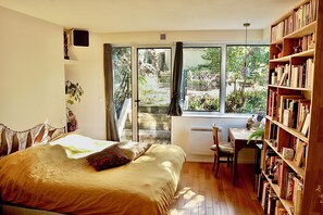 A bedroom with a large bed, a desk, and a bookshelf. - A garden in the city... (Nantes)