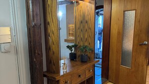 A wooden console with a mirror, a potted plant, and a dog standing in front of it. - Cosy apartment in a quiet neighborhood, close to beautiful nature. (Kópavogur)