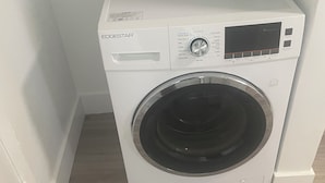 A front-loading washing machine with a control panel, a detergent bottle, and a wooden floor. - Cherry red door cottage with AC in cool Phoenix C (Phoenix)