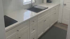 A modern kitchen with white cabinets, a stainless steel sink, a coffee maker, and a built-in microwave. - Cherry red door cottage with AC in cool Phoenix C (Phoenix)