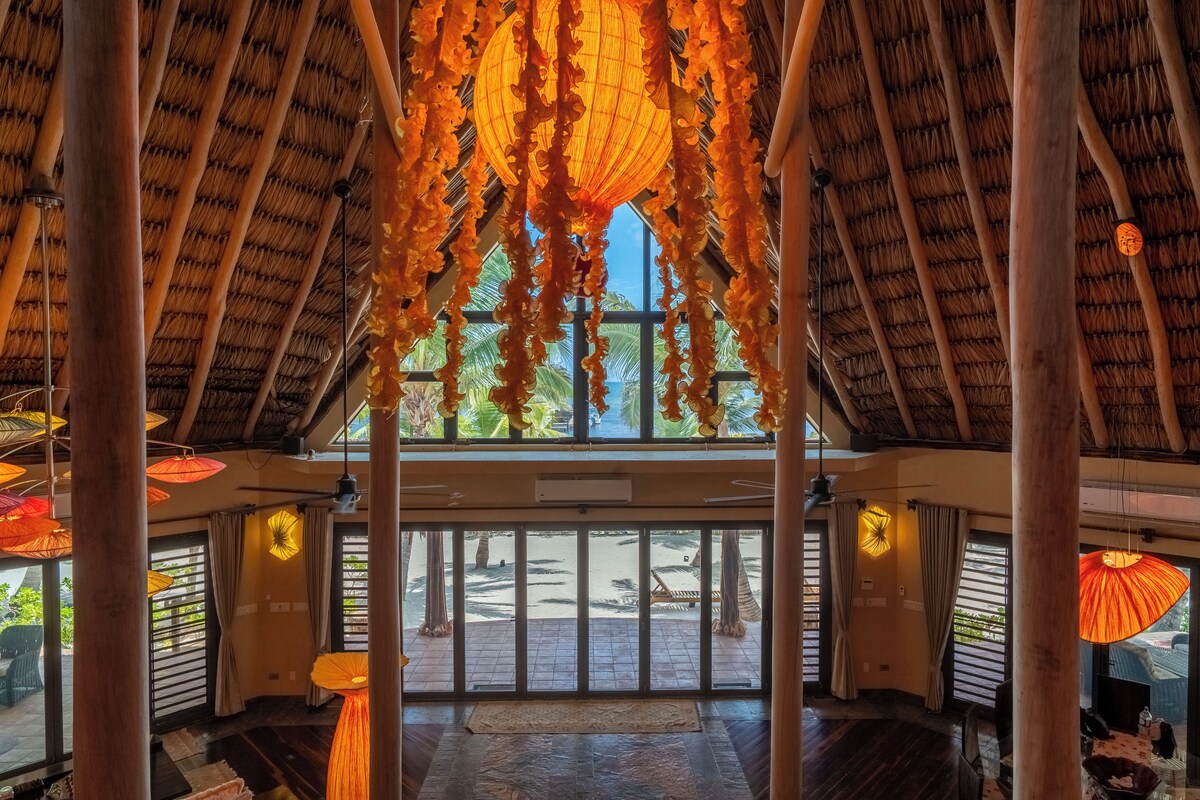 A spacious interior with a high ceiling, large windows, and a view of the beach.