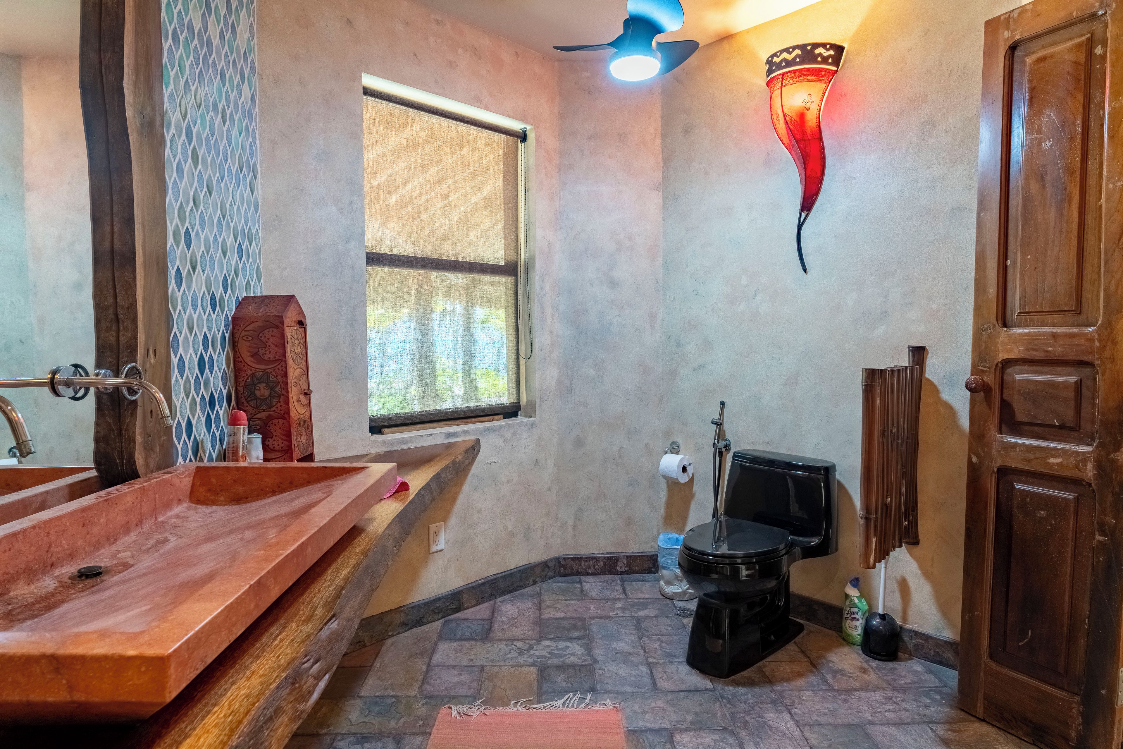 A bathroom with a wooden bathtub, a toilet, and a window.