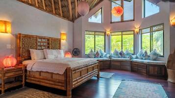 A room with a large bed, a bench with cushions, and a fan.