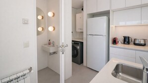 A modern kitchen with white cabinets, a built-in washing machine, a refrigerator, and a countertop with a kettle and a toaster. - Signature Lake View Luxury Residences A01 (San Carlos de Bariloche)