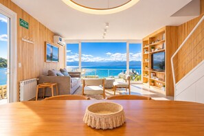 Ein modernes Wohnzimmer mit Holzboden, einem runden Tisch, einer Couch und einem Fernseher auf einem Holzregal.