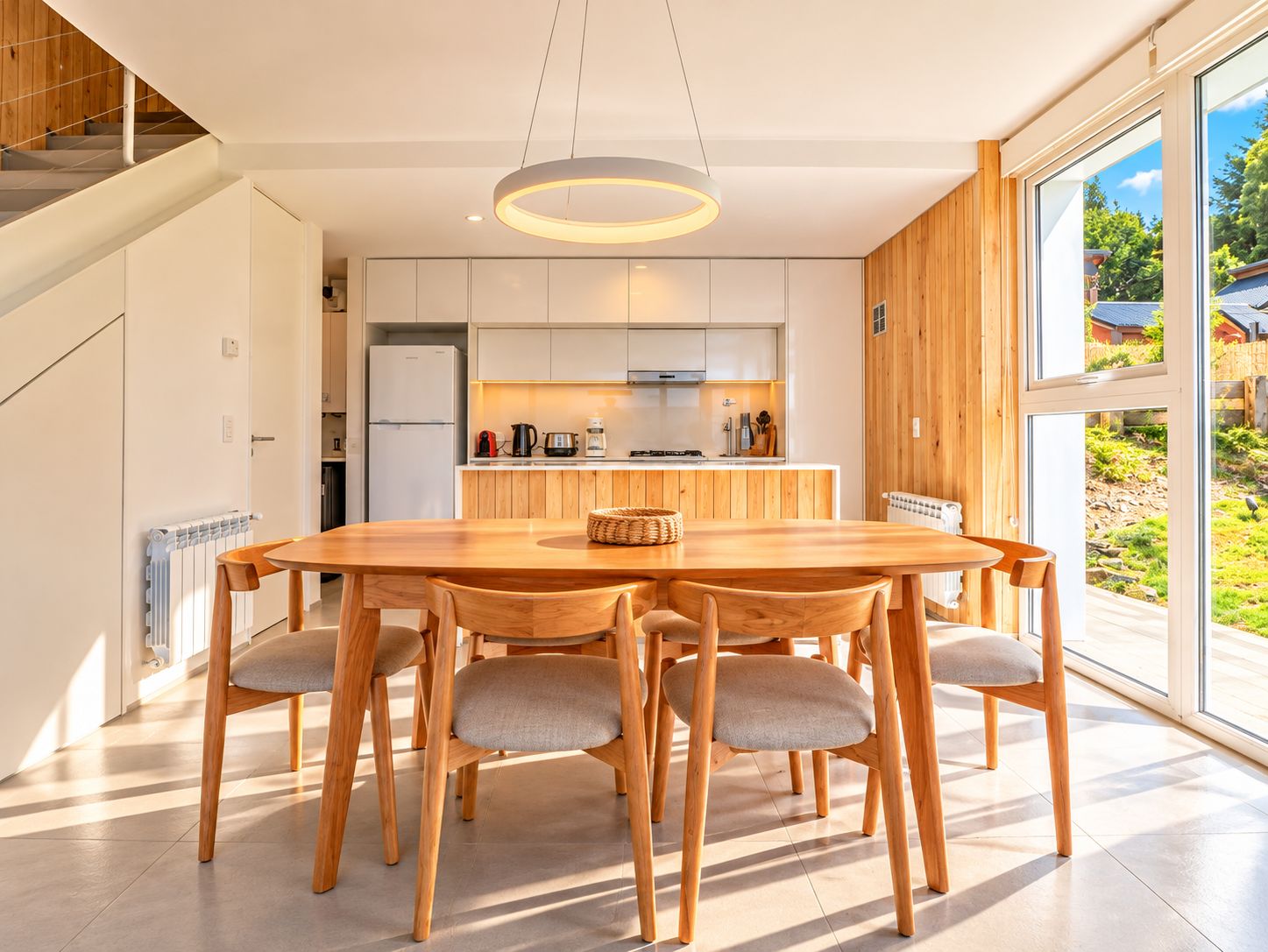 A modern kitchen with white cabinets, a central island, and a dining area with a wooden table and chairs.