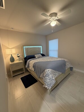 Ein Schlafzimmer mit Bett, Nachttisch, Lampe und Deckenventilator.