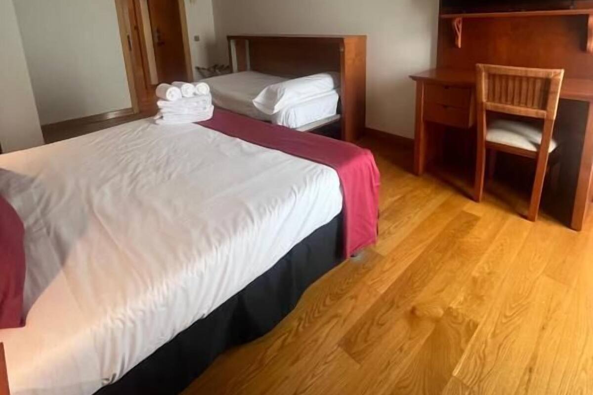 A hotel room with two beds, a desk, a chair, and a flat-screen TV.