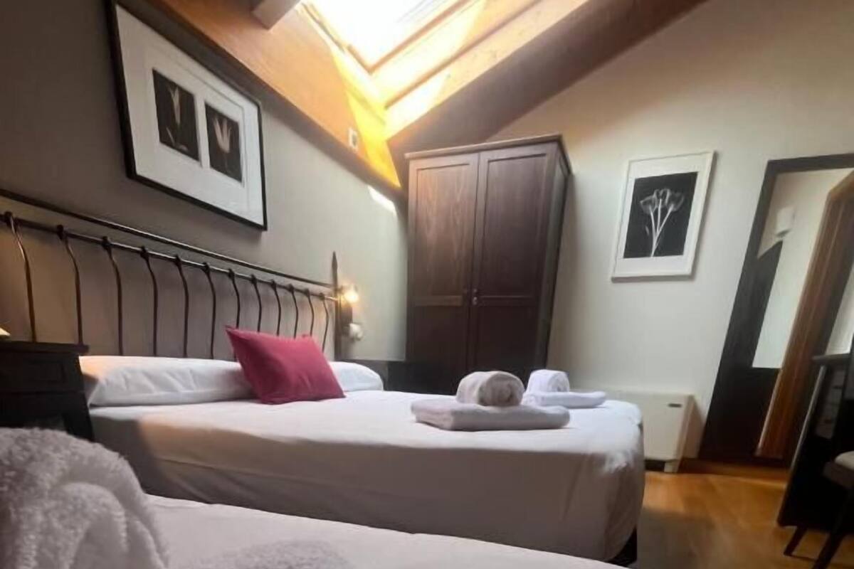 A hotel room with two beds, a wardrobe, and a skylight.