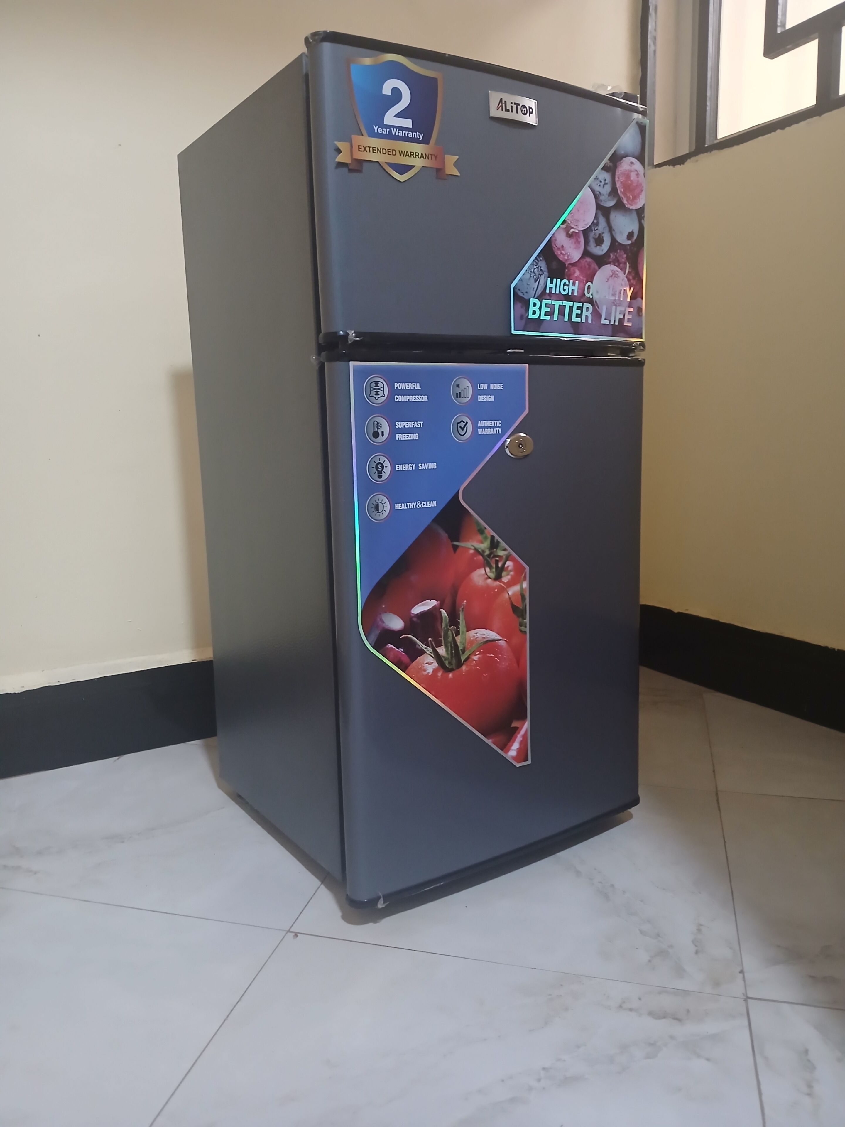 Un refrigerador negro con distintivo de garantía de 2 años, diseño silencioso, congelación superrápida, ahorro energético e icono de limpieza y salud.