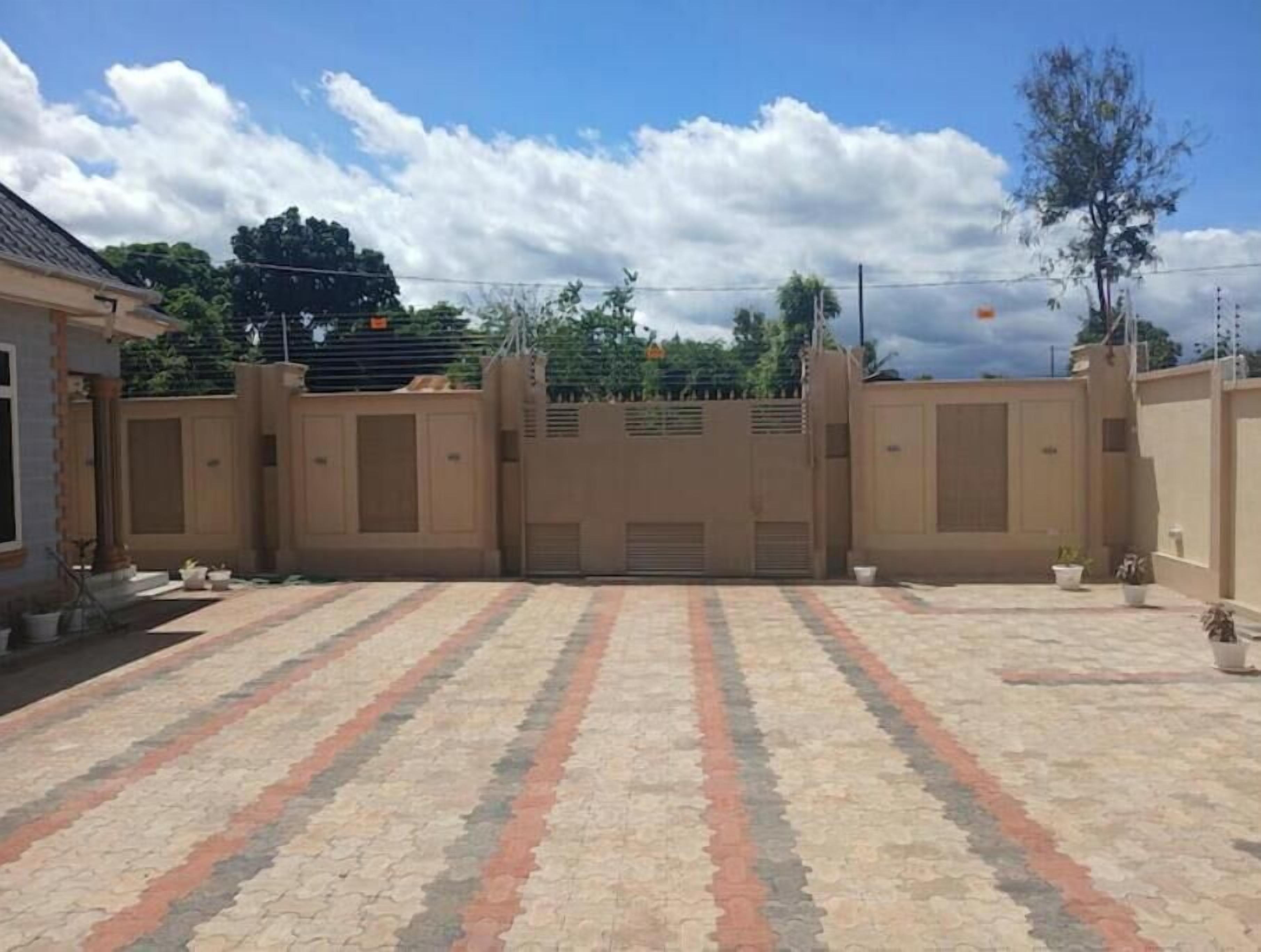 Un patio con suelo de baldosas estampadas, una entrada con reja y un edificio de techo plano.